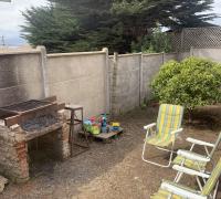 “Sector de asadera dentro del patio, acompañado de un área despejada ideal para reuniones al aire libre y delimitado por cierre perimetral de hormigón.”