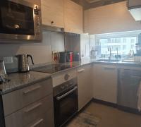 Cocina del departamento con puerta corredera, visible tanto abierta como cerrada, mostrando un espacio funcional e iluminado