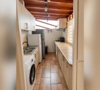 Cocina alargada con muebles a ambos lados, lavaplatos, encimera y techo de madera.