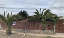 “Frontis de un terreno con dos casas, cercado con un portón corredero de madera y metal.