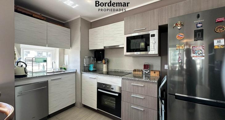 Moderna cocina integrada de gran amplitud, totalmente equipada con encimera, horno empotrado y campana de alta eficiencia