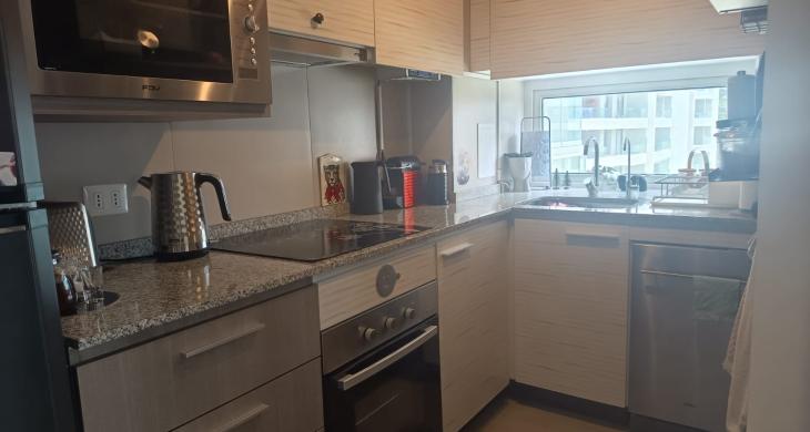 Cocina del departamento con puerta corredera, visible tanto abierta como cerrada, mostrando un espacio funcional e iluminado