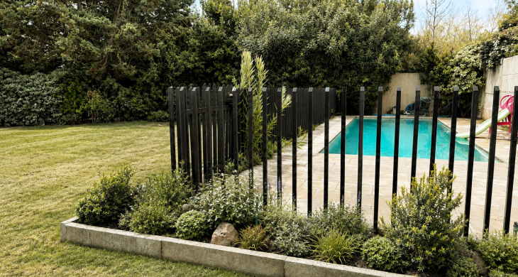 Jardín amplio, piscina cercada y vegetación madura alrededor.